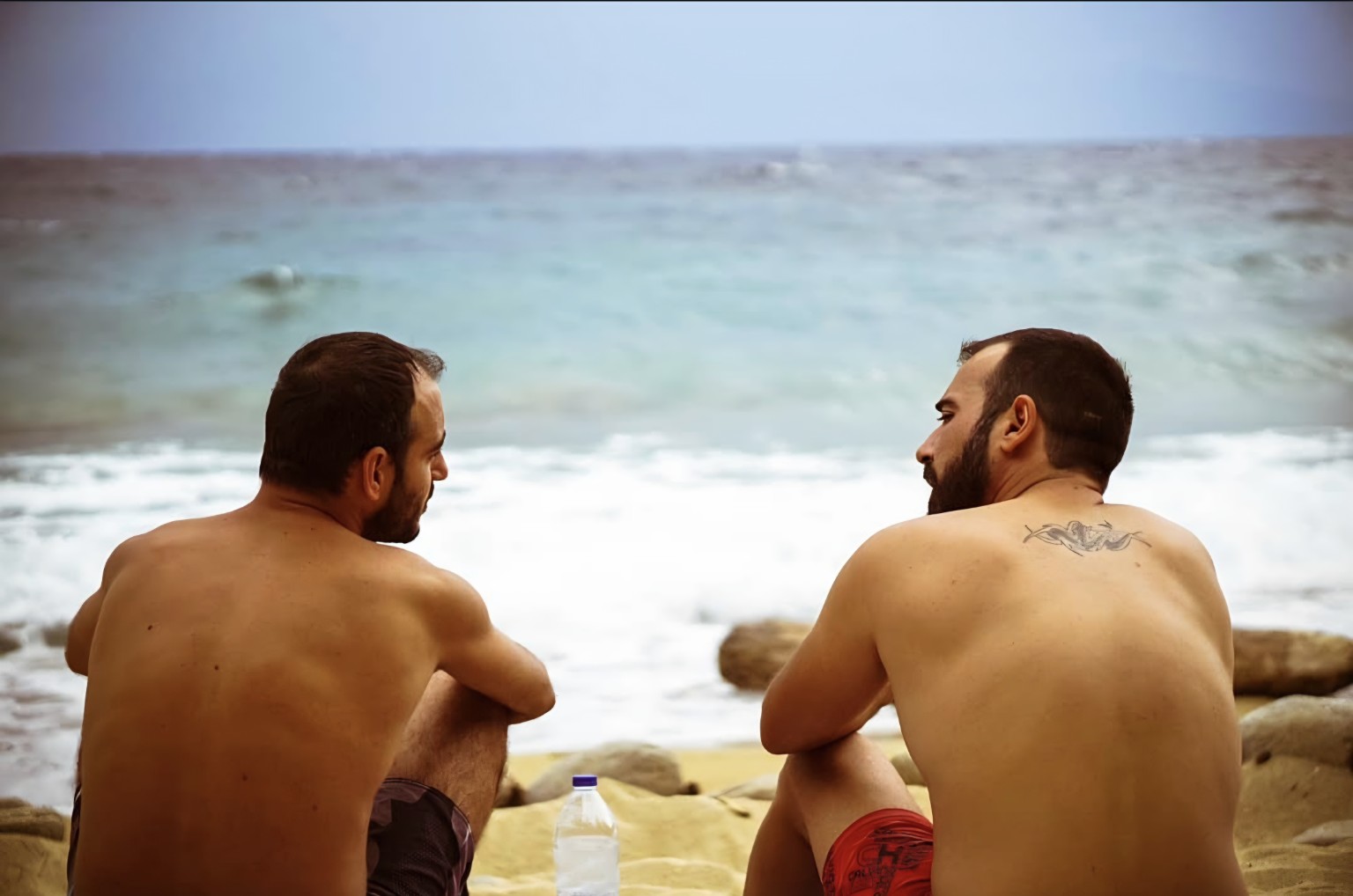 Two men sitting by the sea